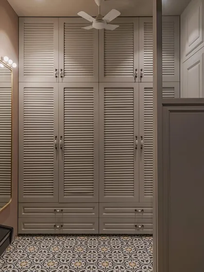 The subtle texture and gentle curves of the louvered shutters add refinement to the space. This wardrobe is a sanctuary of tranquility and elegance, where organization becomes a simple pleasure.