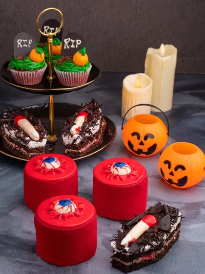 A spooky and fun spread of Halloween-themed desserts, including eyeball pastries and graveyard cupcakes.