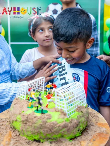 A close-up of the birthday boy admiring his unique football-themed cake, a moment of pure delight.