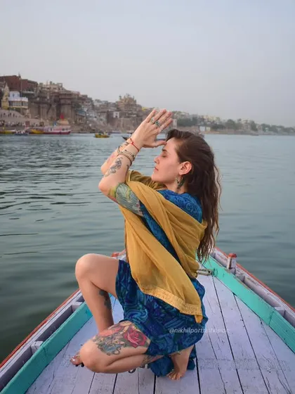 Embracing the soul of Banaras, one breath at a time. A woman in a yoga pose on a boat, connecting with the spiritual energy of the river and the city.