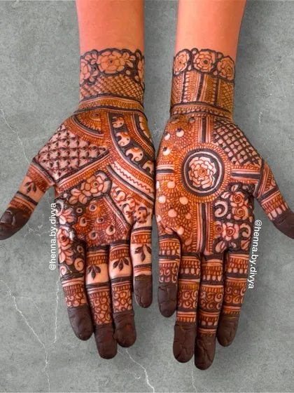A classic full-hand Indian mehendi design. It features a central mandala on one hand and a mix of geometric and floral patterns on the other, providing a balanced look.