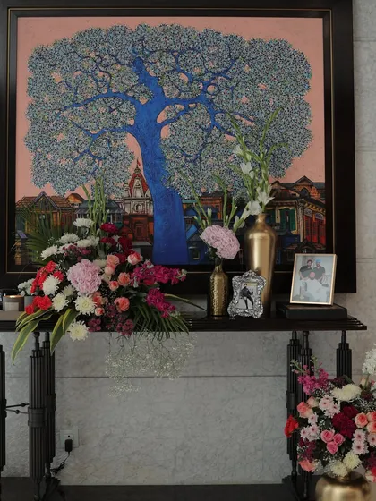 A memory table set up to honor the family. A beautiful piece of art is flanked by photographs of loved ones and lush floral arrangements, creating a personal and heartfelt display.