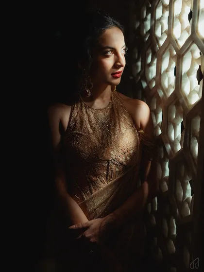 A beautifully composed shot of Tessa by the window. The play of light and shadow accentuates her sculpted features and the richness of her red lipstick.
