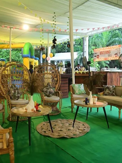 A boho lounge area with wicker peacock chairs and a bouncy castle for the kids.