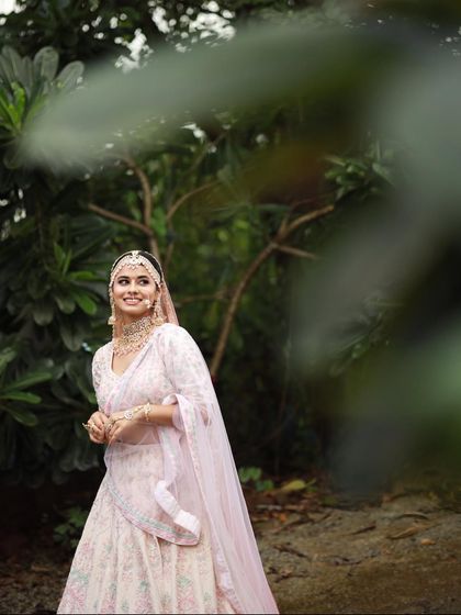A full-length shot of the bride in her beautiful pastel lehenga. The minimal makeup complements the delicate embroidery of her outfit perfectly.