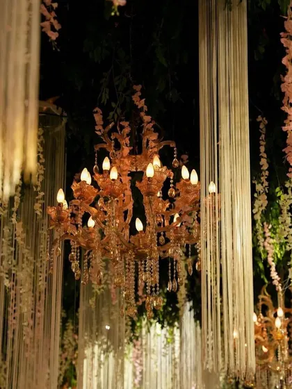A close-up of a beautiful chandelier surrounded by hanging floral strings, a detail that adds depth and romance to the event's ceiling decor.