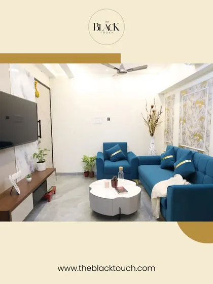 A bright and modern living room with a vibrant blue sofa set and a unique floral-shaped coffee table. The feature wall with textured wallpaper adds a touch of luxury, making the space feel both stylish and welcoming.