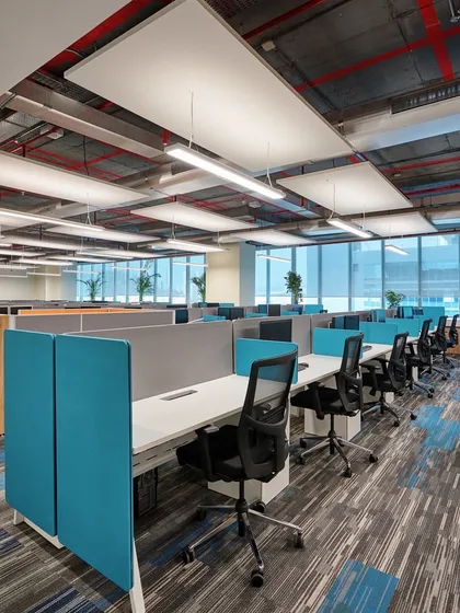A linear workstation arrangement in a large open office. We used suspended acoustic panels and linear lighting to manage noise and provide consistent, comfortable illumination across the floor.