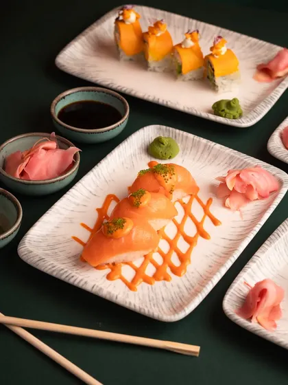 A wider shot of the sushi platter, showing the full context of the plating with wasabi and pickled ginger. This gives a better sense of the overall dish.