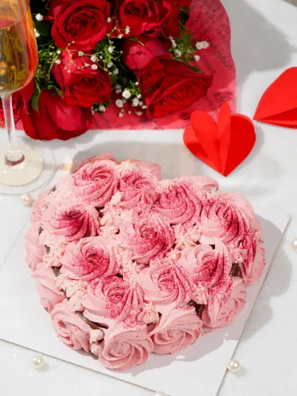 A top-down shot of the heart-shaped cake, styled with roses, champagne, and paper hearts to create a complete Valentine's scene.