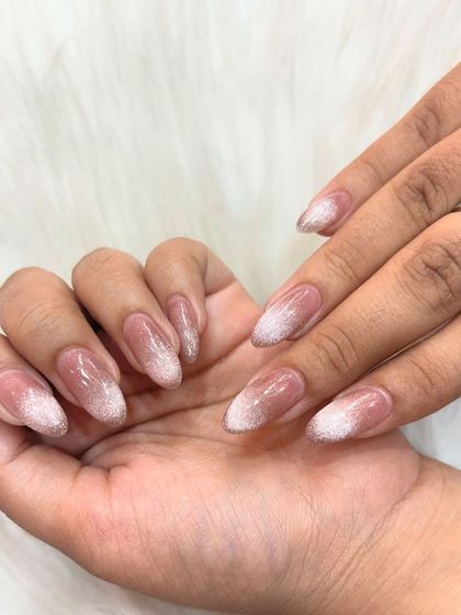 A subtle and sophisticated glitter ombre on almond-shaped nails. The glitter is concentrated at the tips and fades softly towards the base, creating a delicate, sparkling effect.