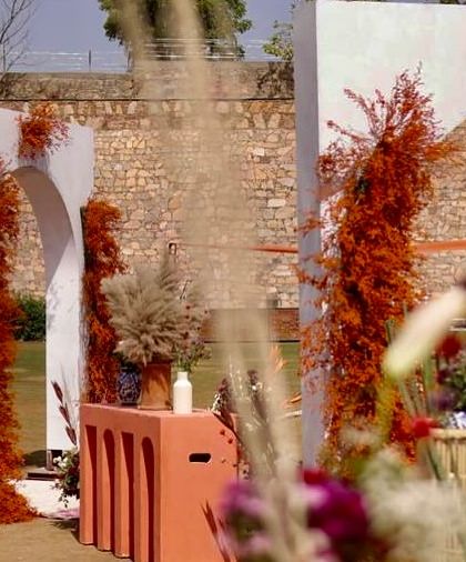 An artfully framed view of the Haldi setup, showcasing the layers of texture from the stone wall, modern arches, and rustic foliage.