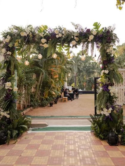 This pre-wedding gala entrance defined minimalist elegance. A lush floral archway made of greenery and deep purple flowers created a sophisticated and welcoming path for guests.