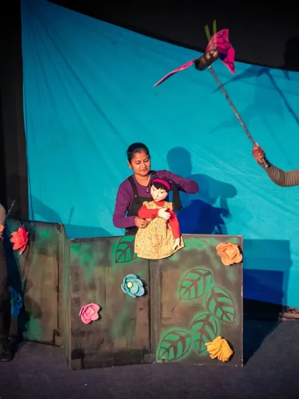 A wide view of the stage during 'Aisha's Journey'. The simple set design and focused lighting draw the audience's attention to the puppets and the story they tell.