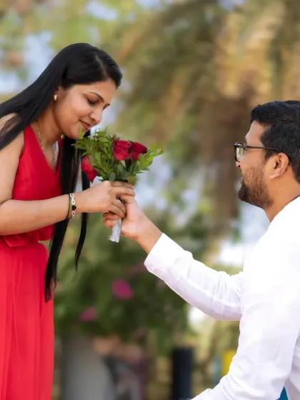 A classic proposal pose with a bouquet of red roses. I made sure to capture her happy expression as she smells the flowers, making the moment feel warm and real.