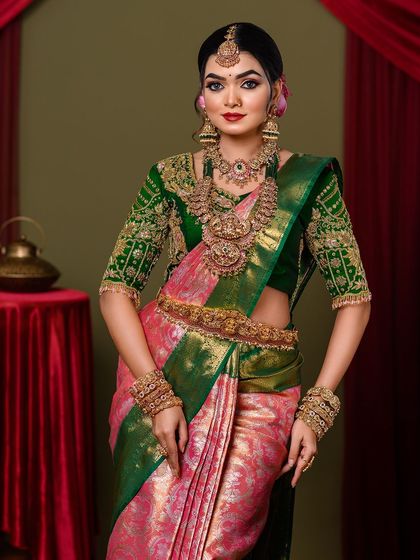 A front-facing portrait of the complete South Indian bridal look, from the maang tikka to the waist belt.