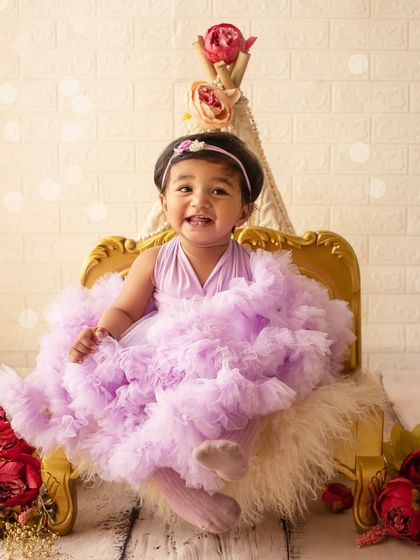 A big, happy grin from the birthday girl, seated on a miniature golden throne. This shot is full of personality and charm.