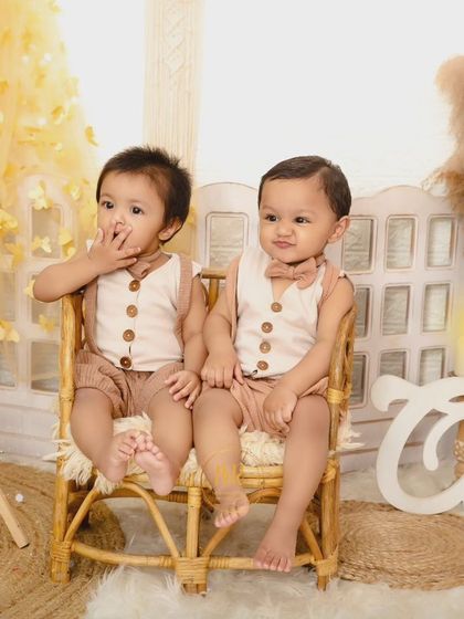 Another adorable shot of twin boys sitting together in a wicker chair for their first birthday photos.