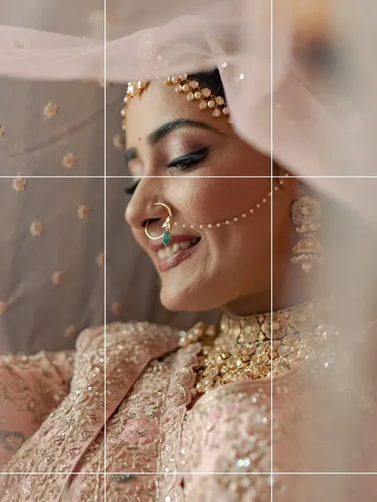 A beautiful, soft-focus portrait of the bride smiling under her veil. The grid overlay adds a modern, artistic touch.
