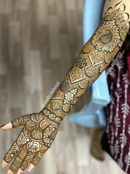 A complete view of Musfira's bridal arm, showcasing the paisley motif and the detailed geometric and floral work.