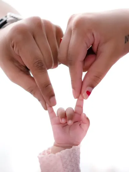 The hands of a mother and father gently join with their baby's tiny hand, forming a symbol of love and connection. This close-up shot focuses on the delicate details that define the newborn stage, turning a fleeting moment into an iconic memory of your family's bond.