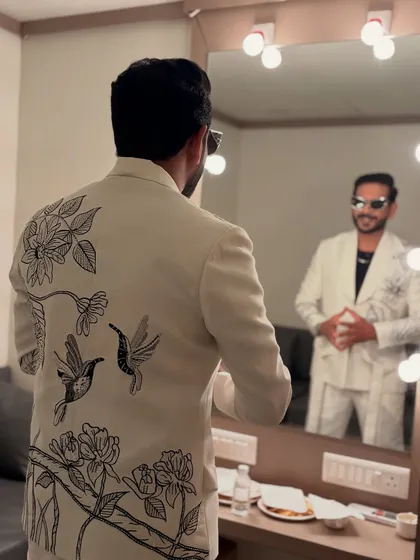 This white suit with delicate black bird and floral embroidery on the back is a great example of subtle elegance. It's a statement piece that's both classic and unique.