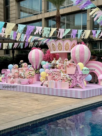 A poolside view of the entire carousel stage, with pastel bunting overhead creating a festive carnival atmosphere.