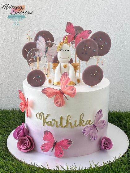 A unique take on the unicorn theme, this cake combines a fondant unicorn with butterflies and chocolate lollipops. The purple ombre frosting adds an elegant touch.