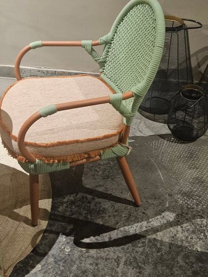A closer look at the craftsmanship of one of our chairs, highlighting the pastel green weaving and comfortable cushion.