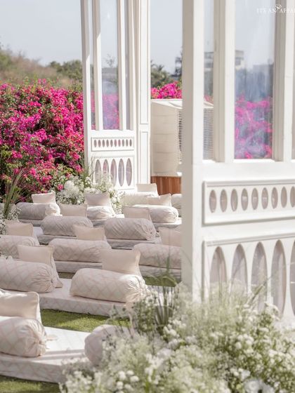 The guest seating area, where modern white structures contrast beautifully with the vibrant pink bougainvillea of the Udaipur venue. The design seamlessly integrates with the natural landscape.