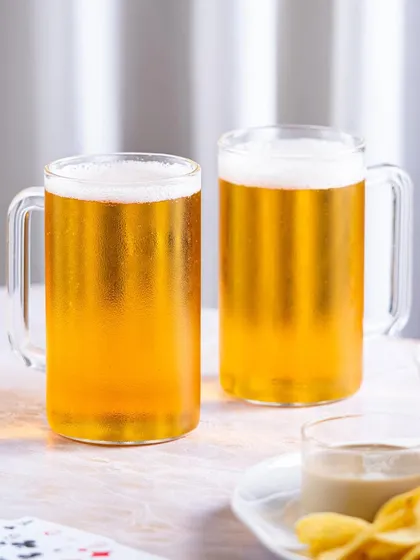 A bright, high-key lifestyle shot of the beer mugs. The soft, airy background gives a feeling of a relaxed afternoon gathering with friends.
