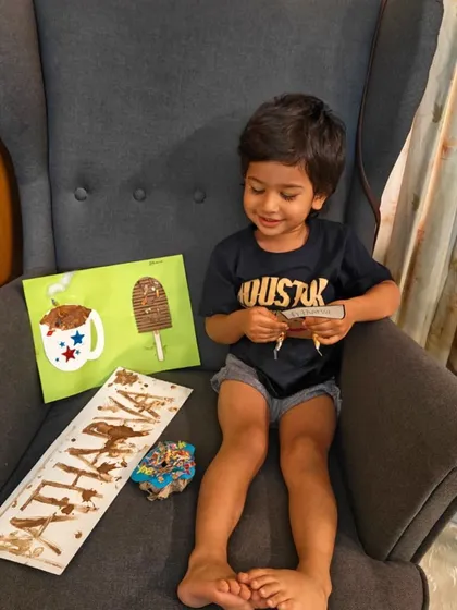 A child proudly displays his creations from our World Chocolate Day workshop. We made chocolate-themed art and even had a little taste, making it a truly multi-sensory celebration.