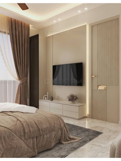 This bedroom in an Ambience Apartment, Gurgaon, uses a calm, neutral palette. The TV wall is simple and elegant, with integrated lighting and a fluted door.
