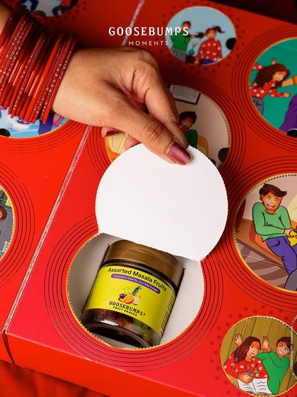 The unboxing of my "Nok Jhok" box is an adventure. Here, a perforated window is opened to reveal a jar of Assorted Masala Fruit, turning the gift into an interactive experience that brings back childhood memories.