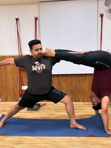 Two students demonstrate great strength and balance in this partner pose, a combination of a handstand variation and warrior pose.