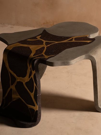 The full form of our coral center table, showcasing its unconventional shape and the stunning contrast between the dark terrazzo and the fluid brass inlay. It's a perfect piece for a modern, art-focused interior.