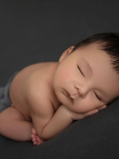 Simplicity at its finest. A newborn baby in the side lying pose on a simple, dark grey backdrop, allowing all the focus to be on their perfect form.