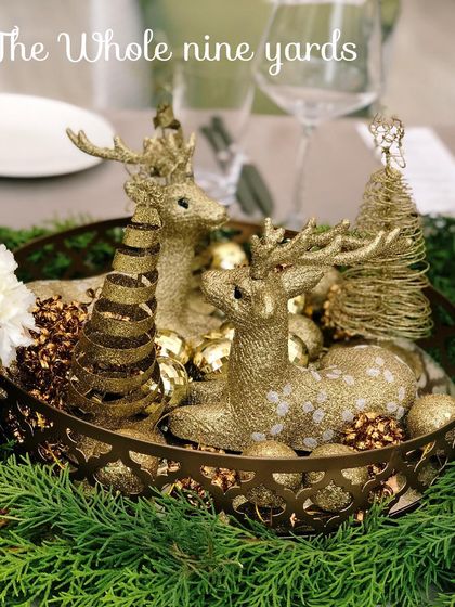 A charming Christmas centerpiece featuring golden, sparkling reindeer figurines nestled in a basket with ornaments, surrounded by fresh pine.