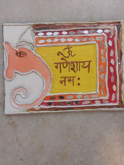 This is a beautiful example of Lippan art Ganesha, decorated with mirrors and vibrant colors. It's a wonderful alternative to clay sculpting for those who love painting and design.
