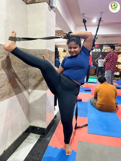 A smiling student enjoying her supported split practice. The belt allows her to control the stretch and work on her flexibility with confidence.