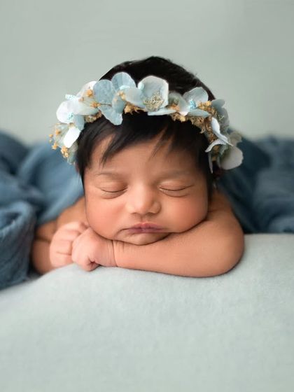 The 'head on hands' pose is a client favorite. It's perfect for showing off a baby's delicate features, especially when framed by a soft wrap and floral headband.