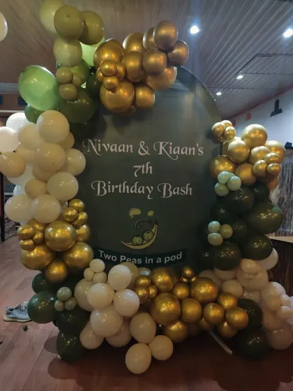 A sophisticated birthday bash for twins, featuring a custom backdrop and an organic balloon arch in olive green, gold, and white.