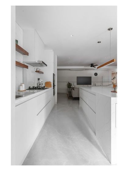 This view down the galley kitchen shows the minimalist design, with handleless white cabinets and a seamless look that extends into the living area.