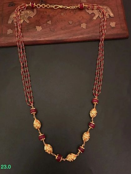 A multi-strand beaded necklace in a rich maroon color. The necklace is made from 92.5 silver with gold plating and features beautiful leaf-shaped golden beads.