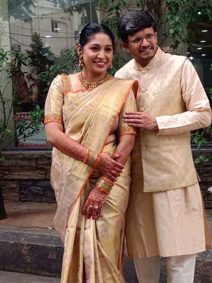 A candid photo of Geeta and her husband. The golden tissue silk saree radiates a timeless charm, perfect for wedding festivities.