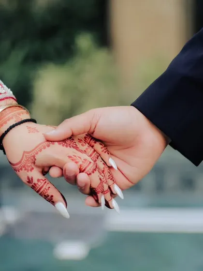 A symbolic shot of the couple holding hands, showcasing the bride's beautiful henna. This simple gesture represents their promise and connection.