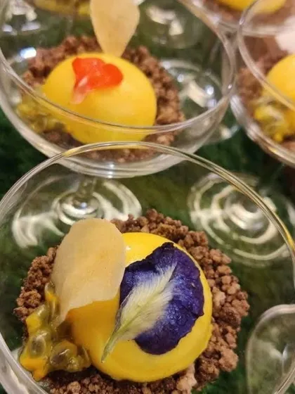 A stunning Mango Mascarpone dome with dark chocolate, passion fruit jelly, and edible flowers. Our desserts are crafted to be the perfect, beautiful finale to a special meal.