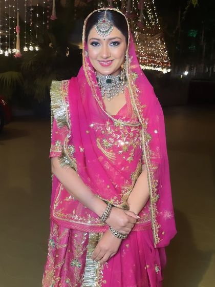 A pretty-in-pink traditional Rajputi Poshak look. The makeup is soft and regal, with a focus on defined eyes to complement the traditional jewelry and headwear.