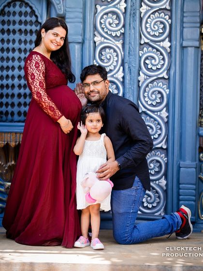 A classic family pose with a playful twist. The father leans in to "listen" to the baby bump, creating a fun and memorable photo with their daughter.