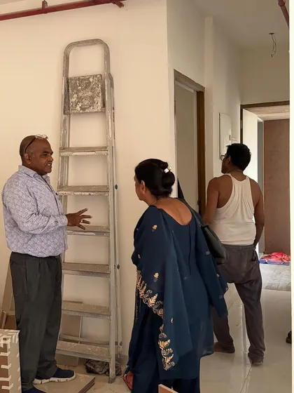 Clients discussing their requirements on-site, with a ladder and construction materials indicating the active work phase.